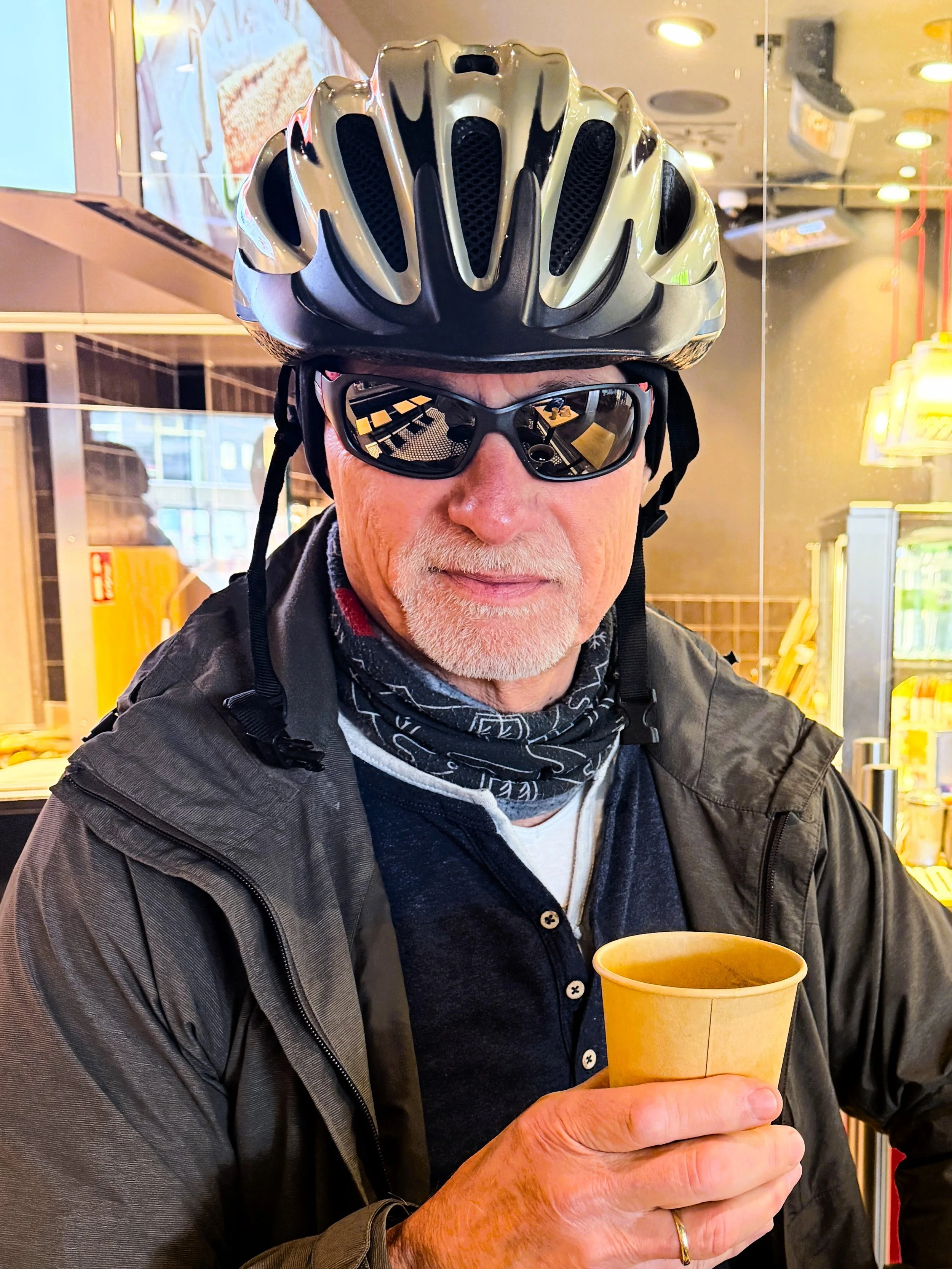Berliner Bezirke mit dem Fahrrad erkunden, Mann mit Fahrradhelm und Kaffeebecher
