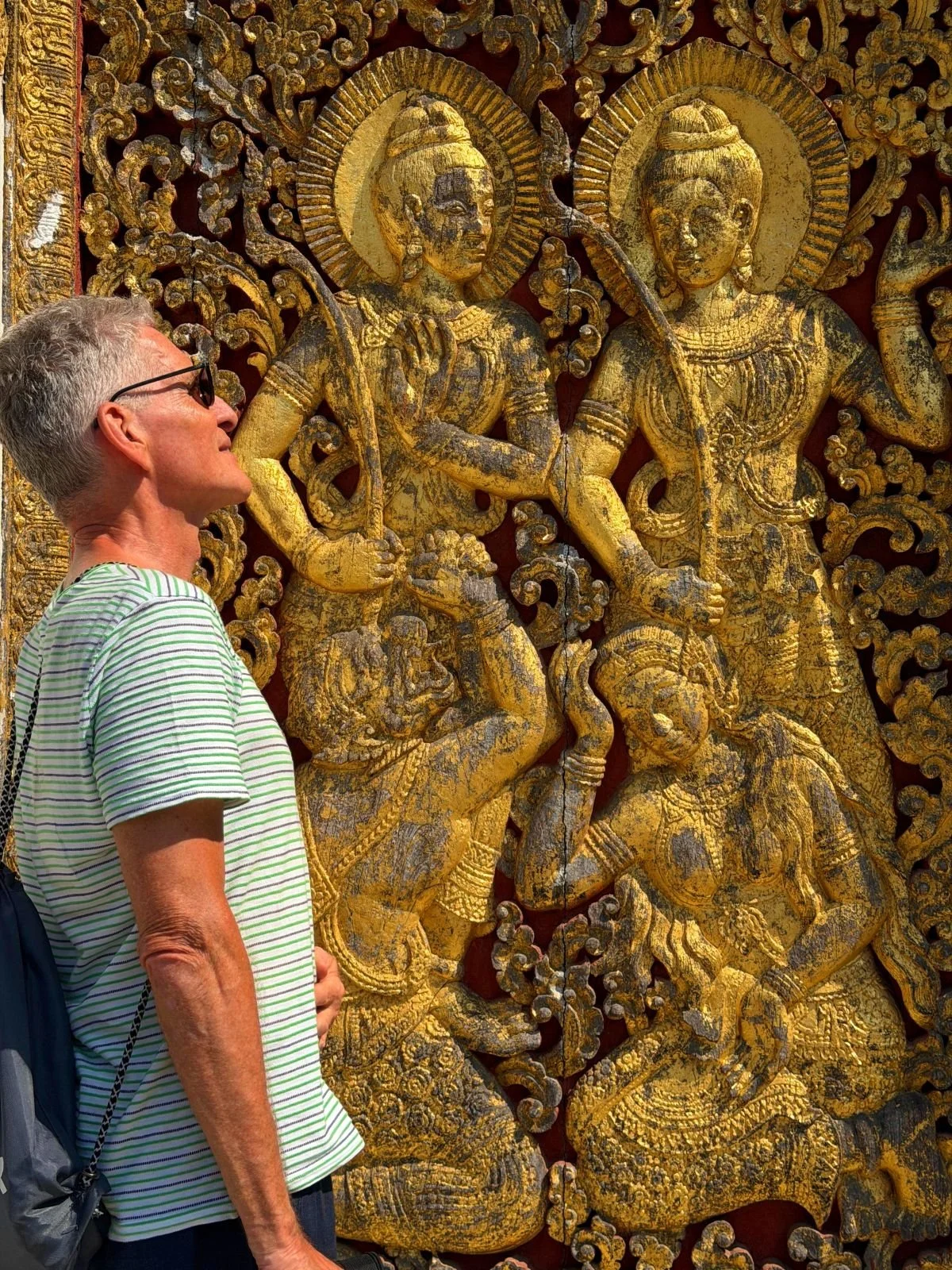 Laos - Rundreise auf eigene Faust - Mann steht vor goldverzierter Tempel-Tür in Luang Prabang