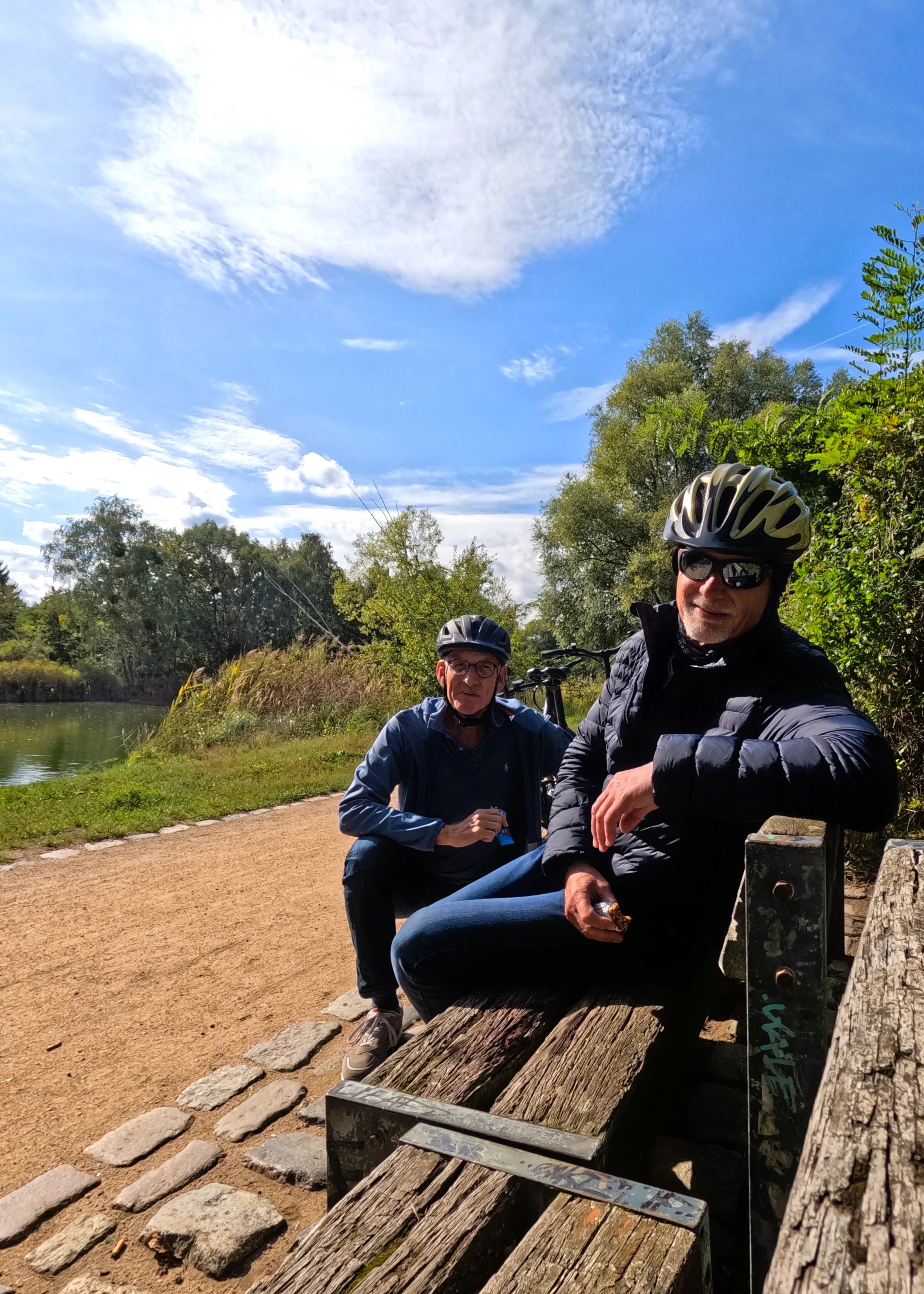 E-Bike-Test, zwei Männer auf einer Bank mit See im Hintergrund