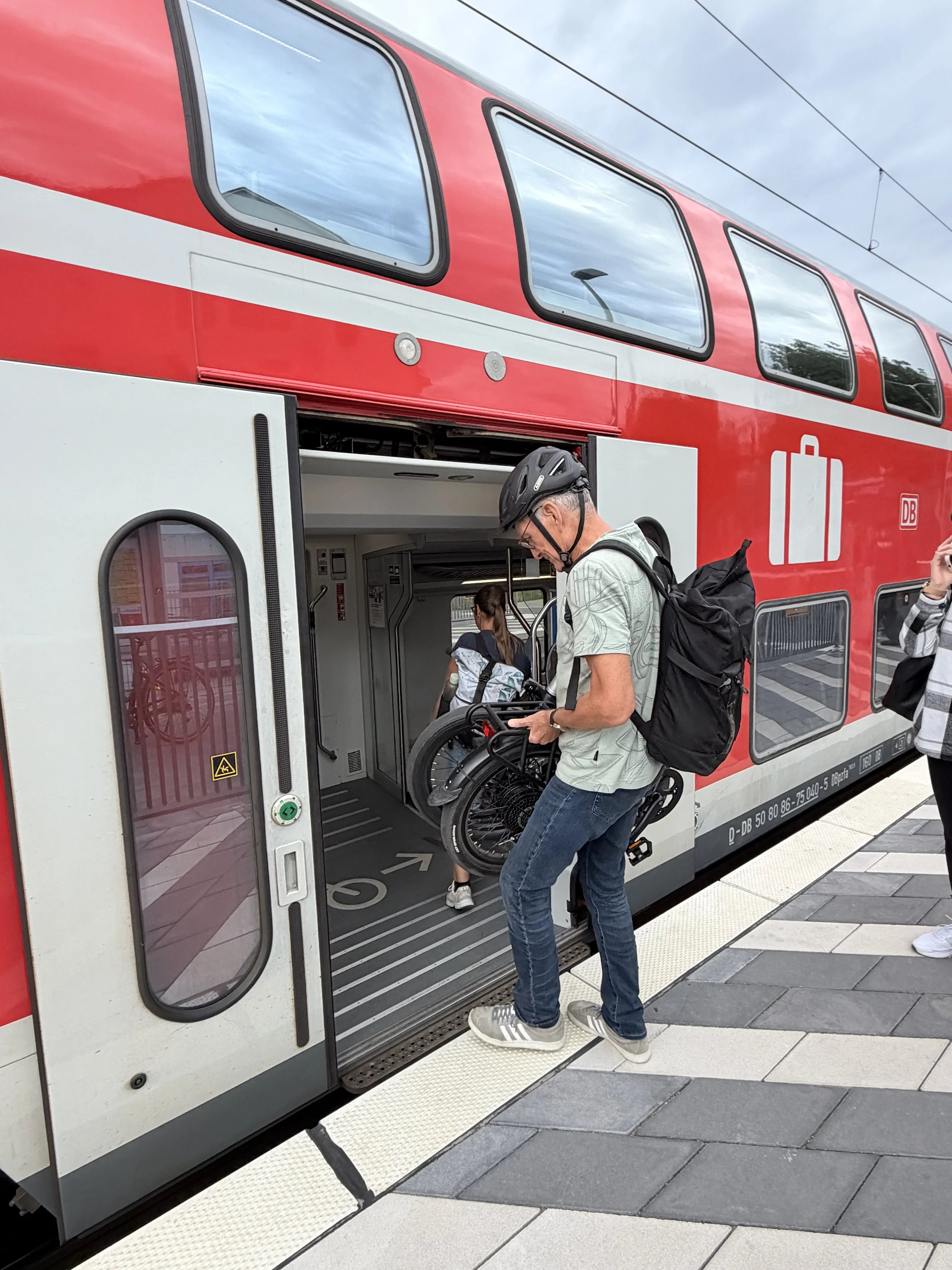 Genießen statt anstrengen – E-Bike-Test, Mann mit Faltrad in der Hand in Zug einsteigend