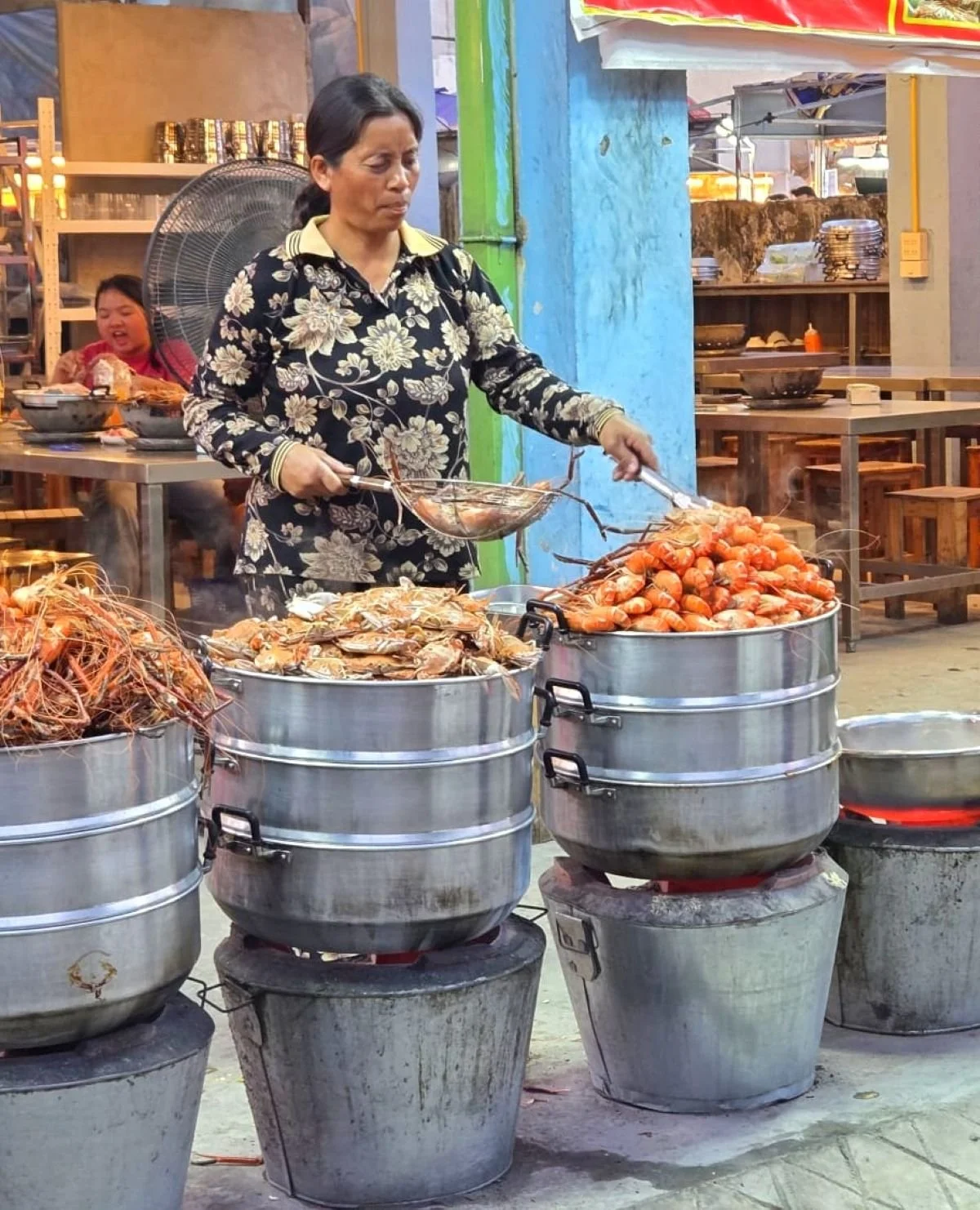 Laos - Rundreise auf eigene Faust - Verkäuferin auf Nachtmarkt in Vientiane vor Tonnen mit Bergen von Meeresfrüchten