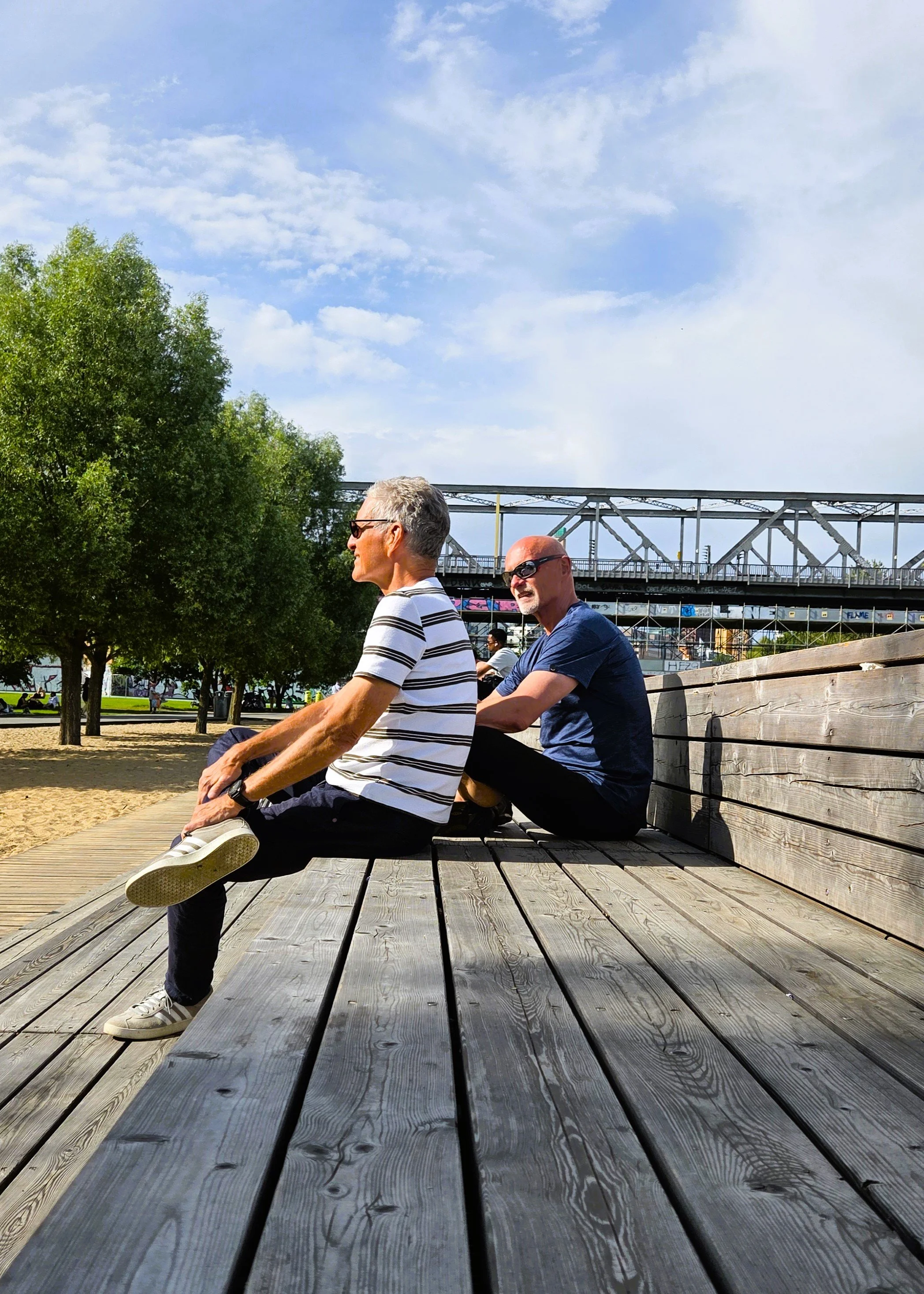 Auf dem Rad im Park am Gleisdreieck – die schönsten Parks in Berlin, zwei Männer auf einer Holzbank sitzend