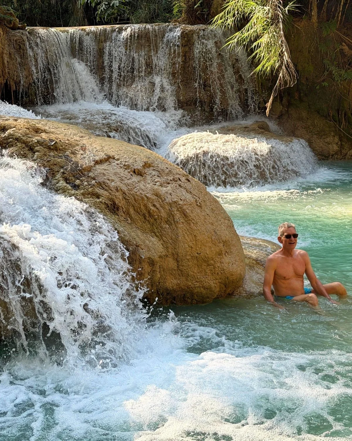 Laos - Rundreise auf eigene Faust - Mann badet im Wasserbecken am Wasserfall Kuang Xi
