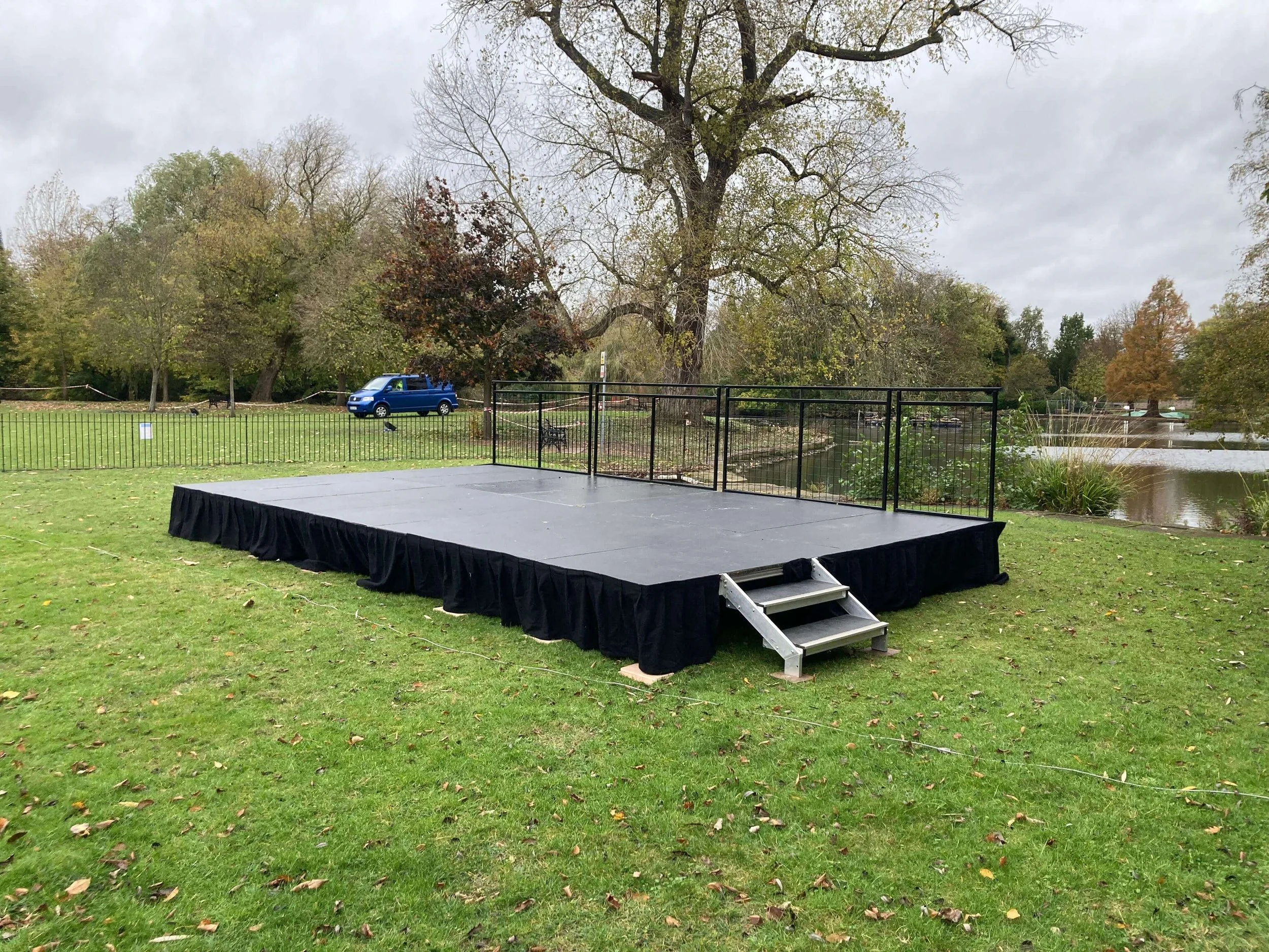 Low-profile outdoor modular riser stage with access stairs set up on grass park ground