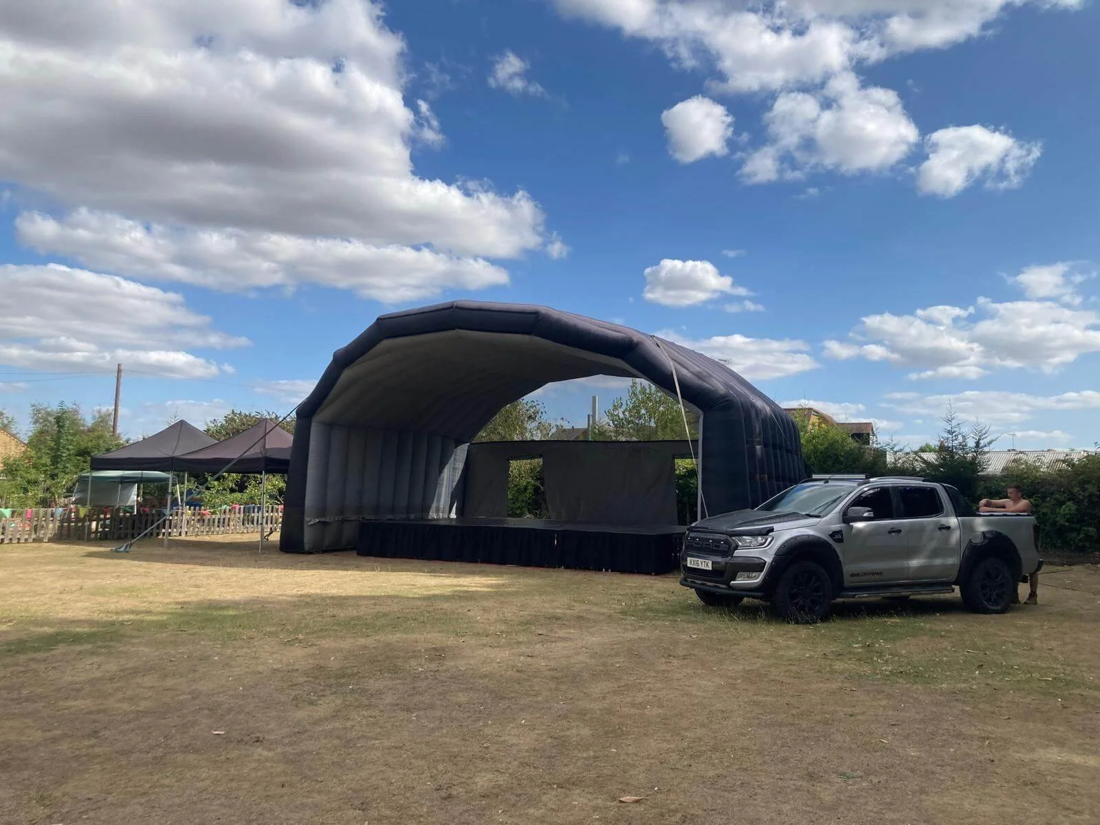Large inflatable arched canopy outdoor event stage setup with transport vehicle