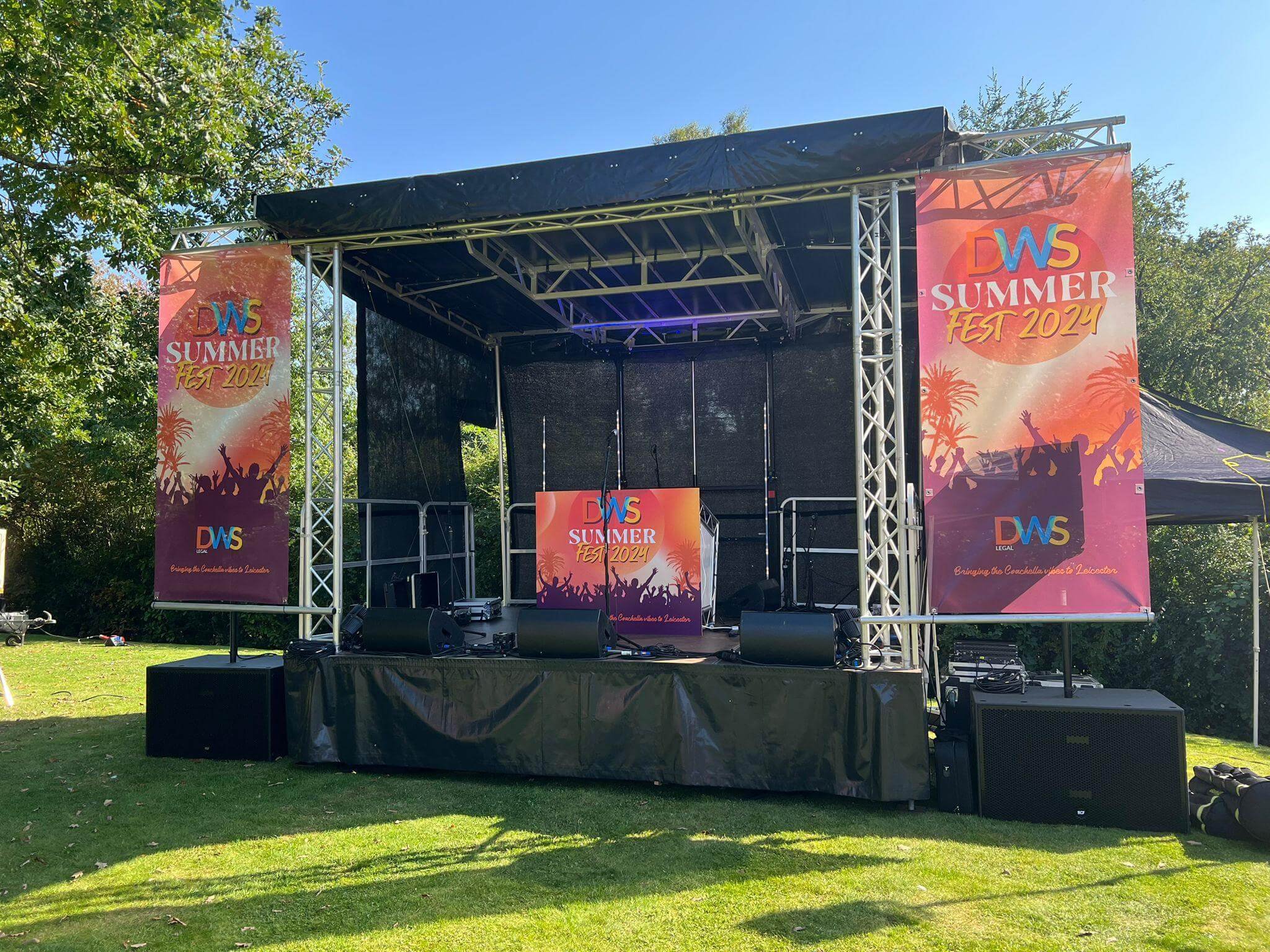 Covered festival stage hire with custom side branding banners and stage lighting truss