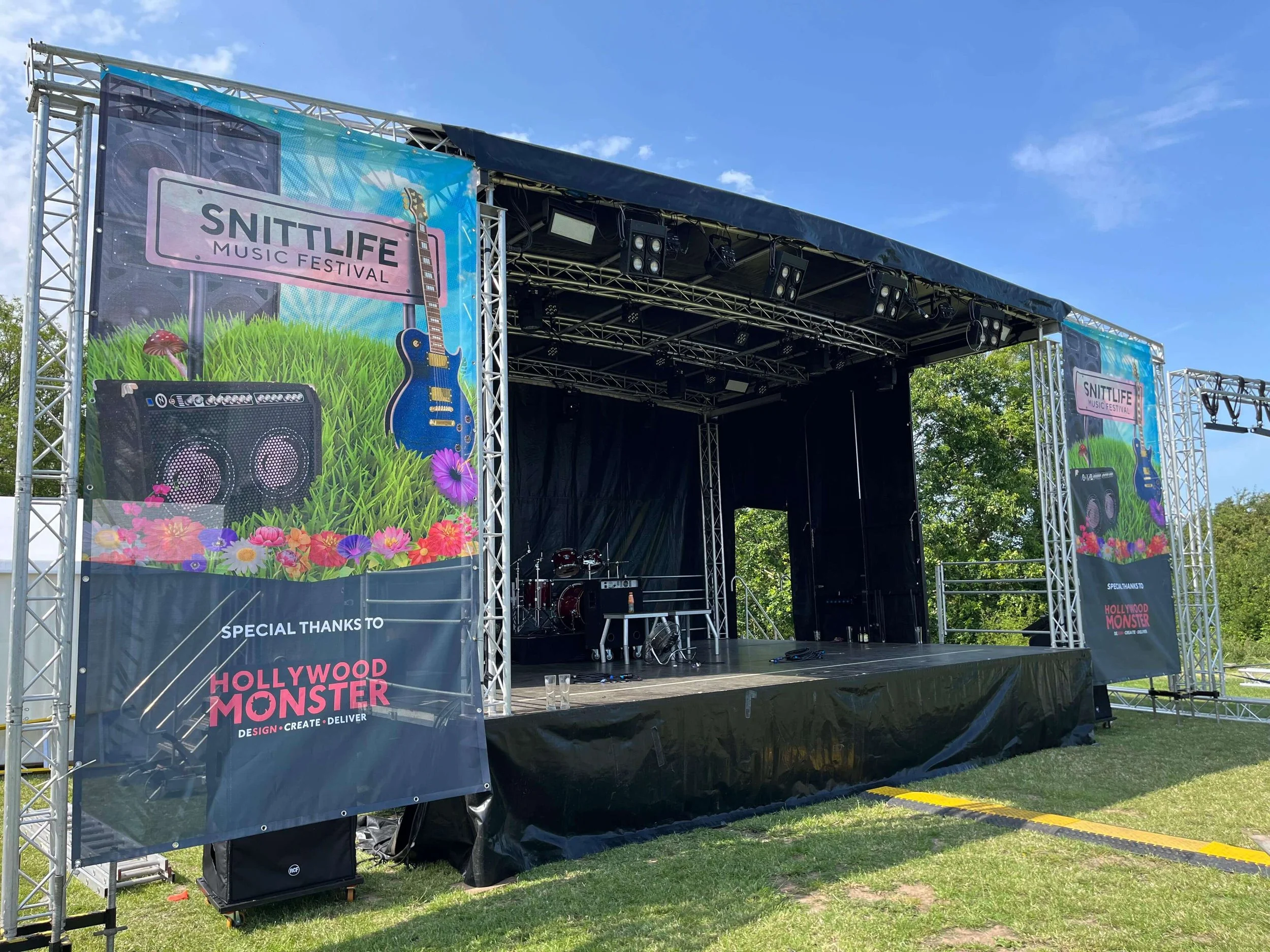 Outdoor concert stage hire with Snittlife event branding banners set up on field