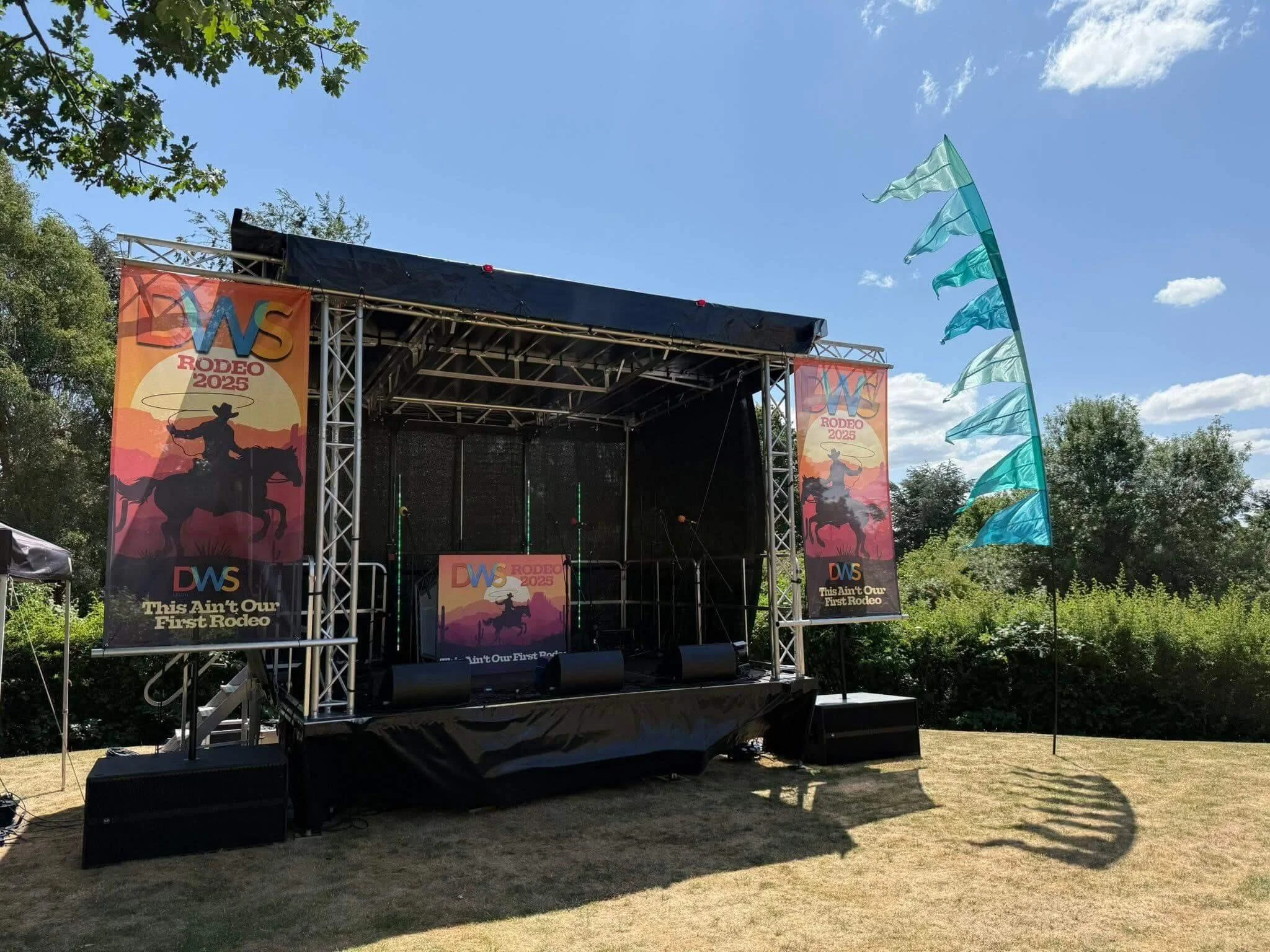Professional mobile stage setup with event branding banners and feather flags outdoors