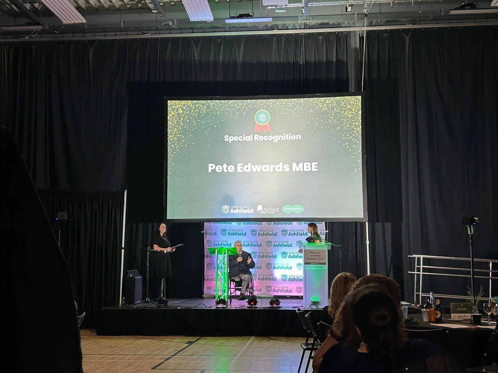Indoor corporate event stage setup with projector screen display and presentation podium
