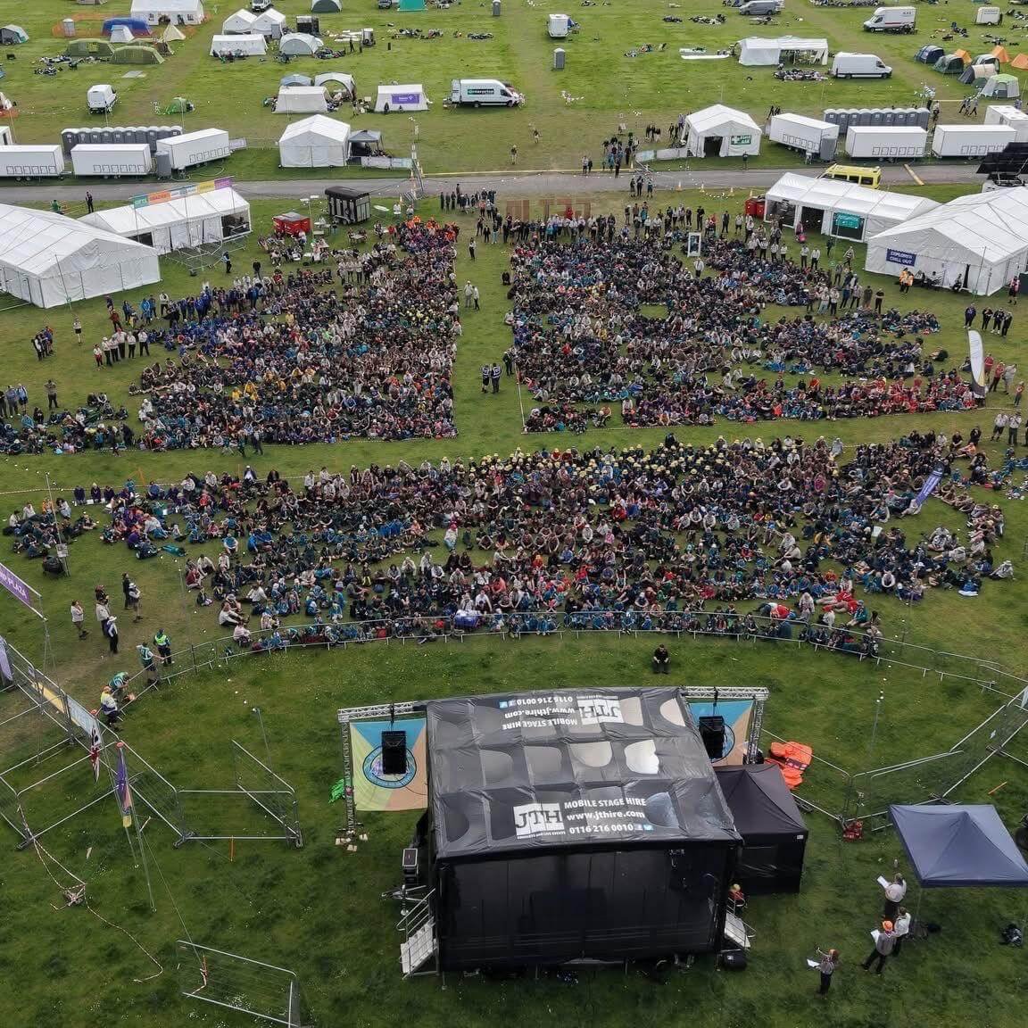 Aerial view of large outdoor festival crowd gathered in front of JTH main event stage
