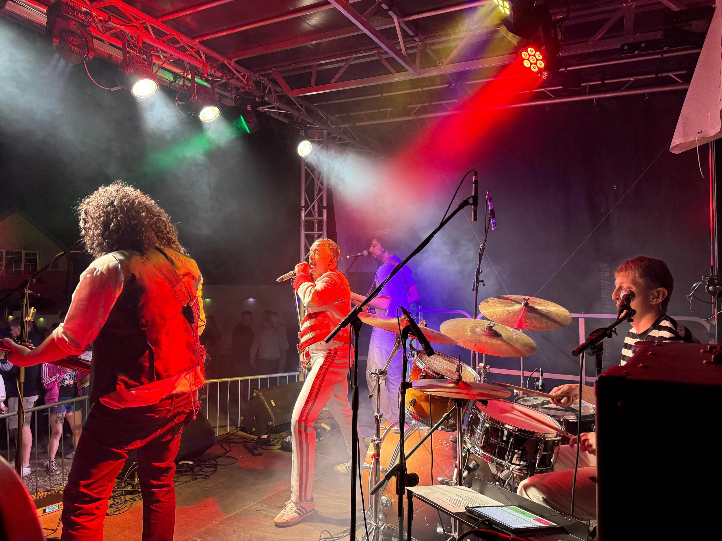 Live band performing on stage under red and green concert lighting effects