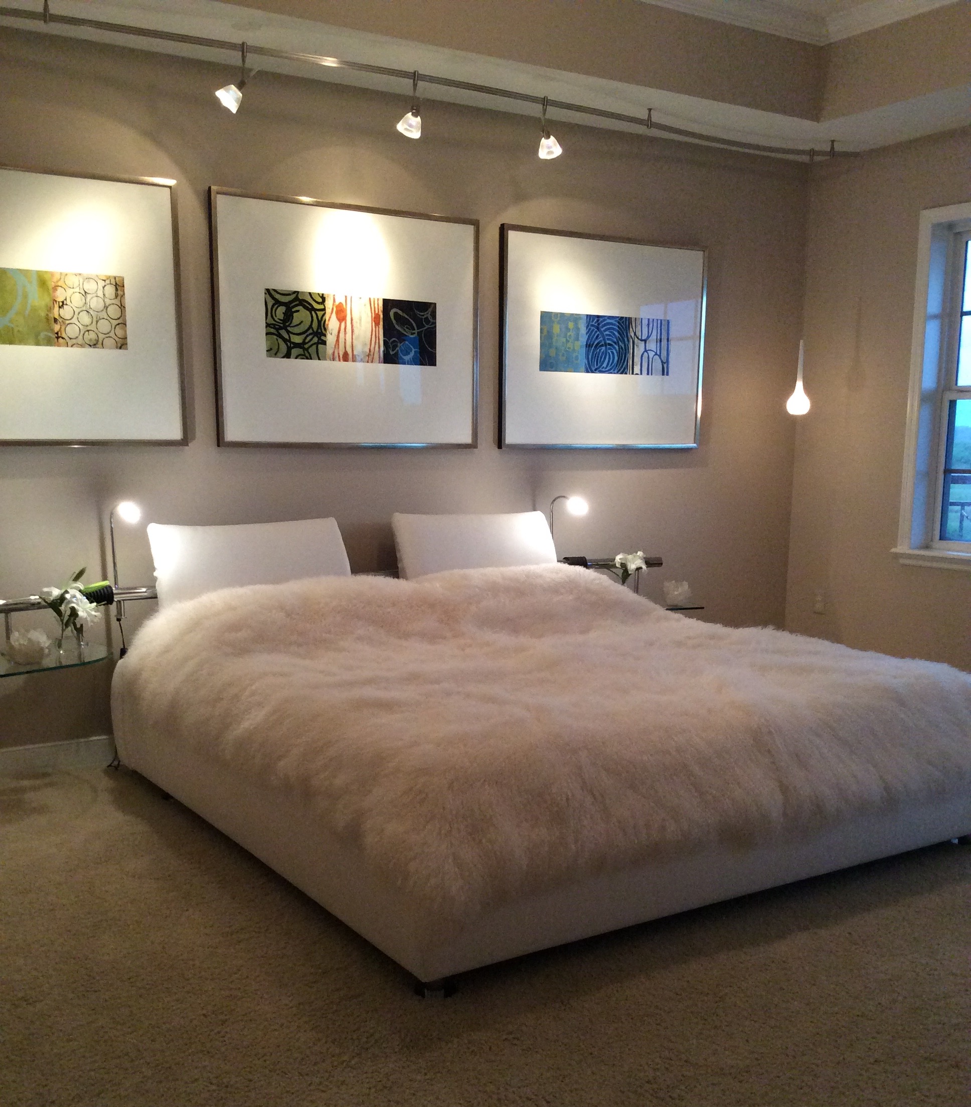 The master bedroom suite features a modern bed with pivoting glass side tables and a Mongolian curly sheep's throw.