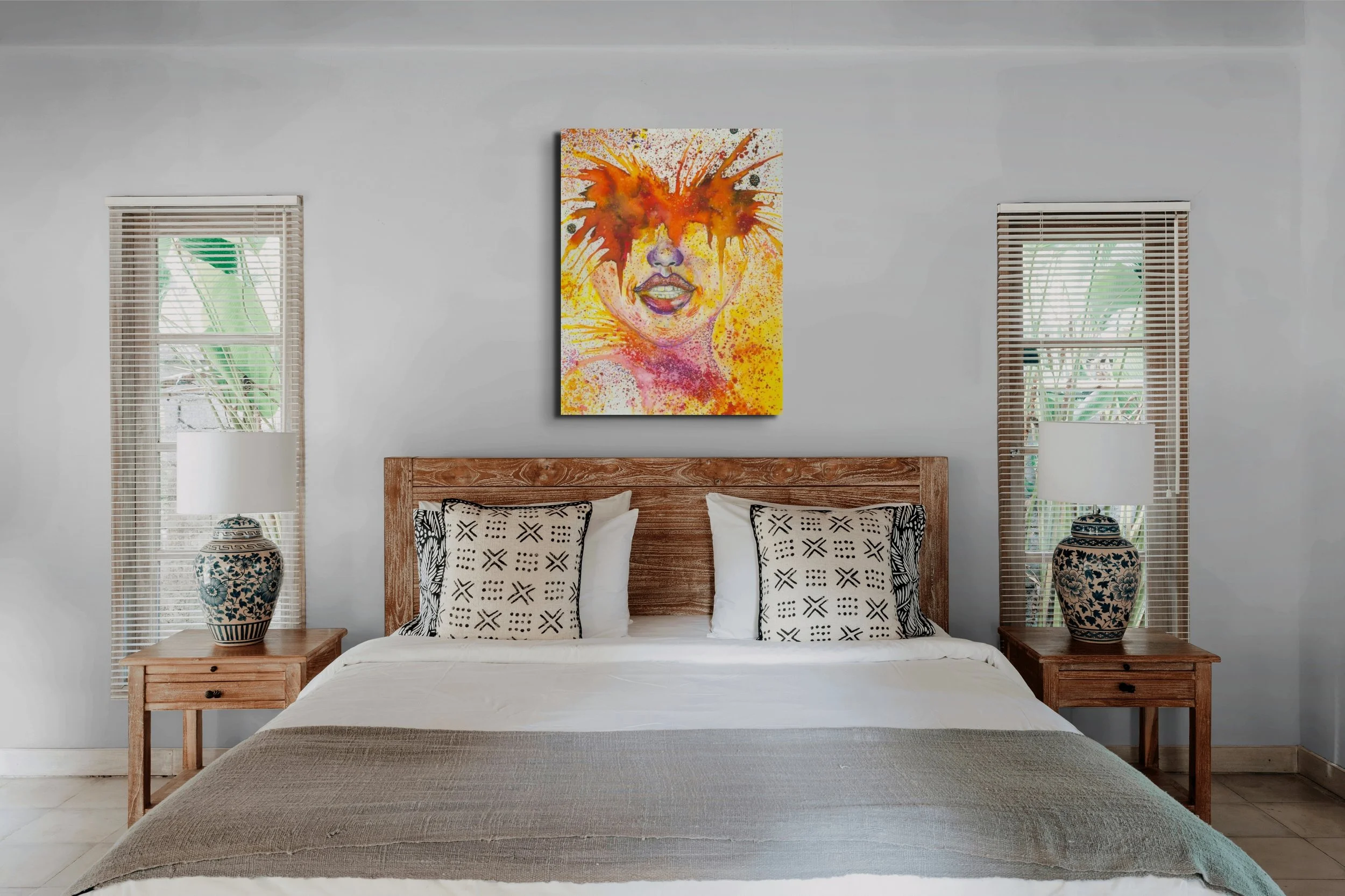 Orange and yellow abstract feminine portrait wall art hanging above a bed in a bright modern bedroom with artistic home decor styling.