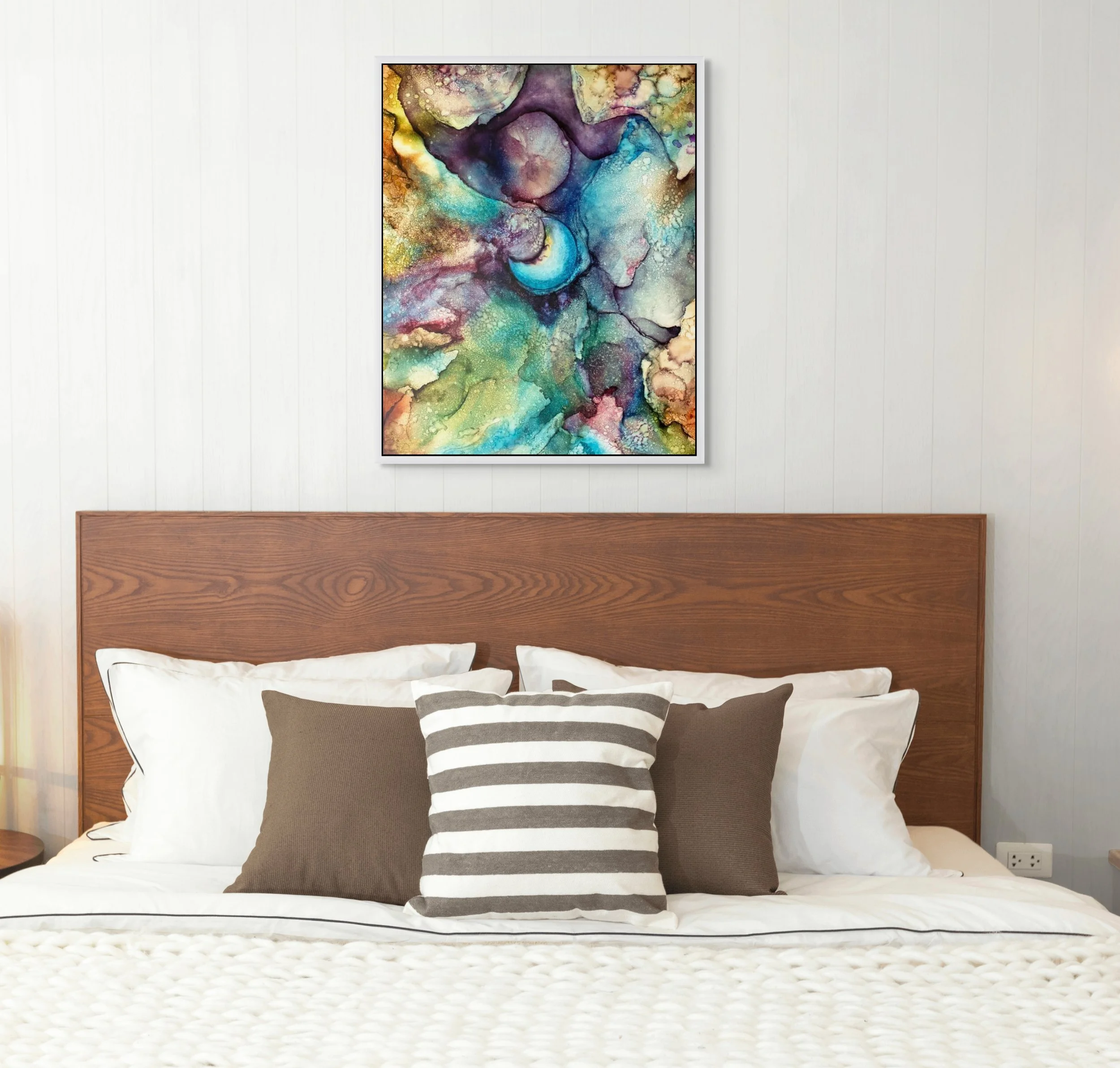 Abstract alcohol ink wall art above a neutral bed in a modern bedroom. Colorful contemporary home decor with ethereal teal, purple, gold, and turquoise textures.