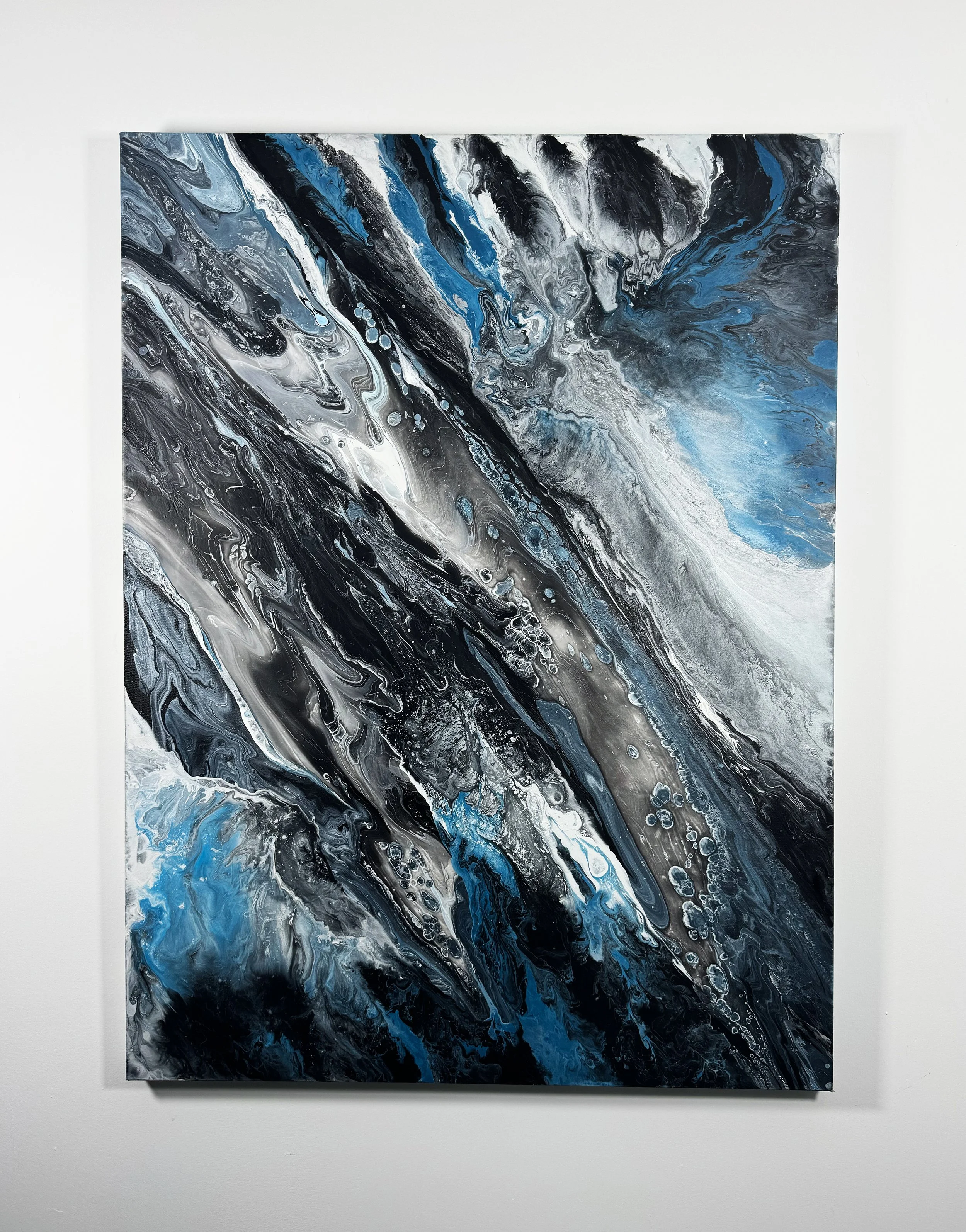 Large contemporary abstract painting with swirling black, white, silver, and blue acrylic textures inspired by ocean waves, storms, and cosmic movement for modern wall decor.