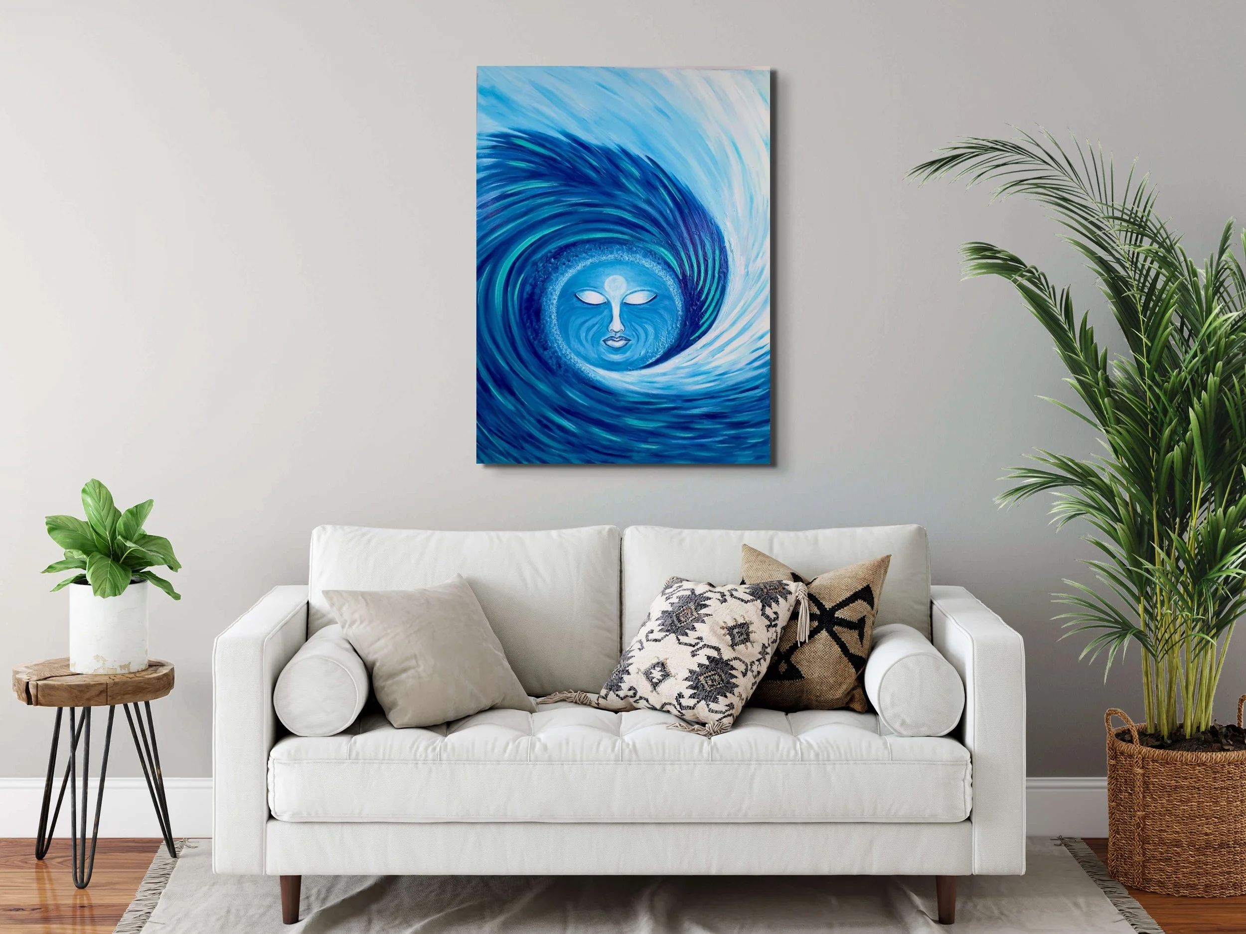 Blue abstract wave wall art above a white sofa in a modern coastal living room. Ocean-inspired home decor featuring a glowing moon face and textured blue wave painting.