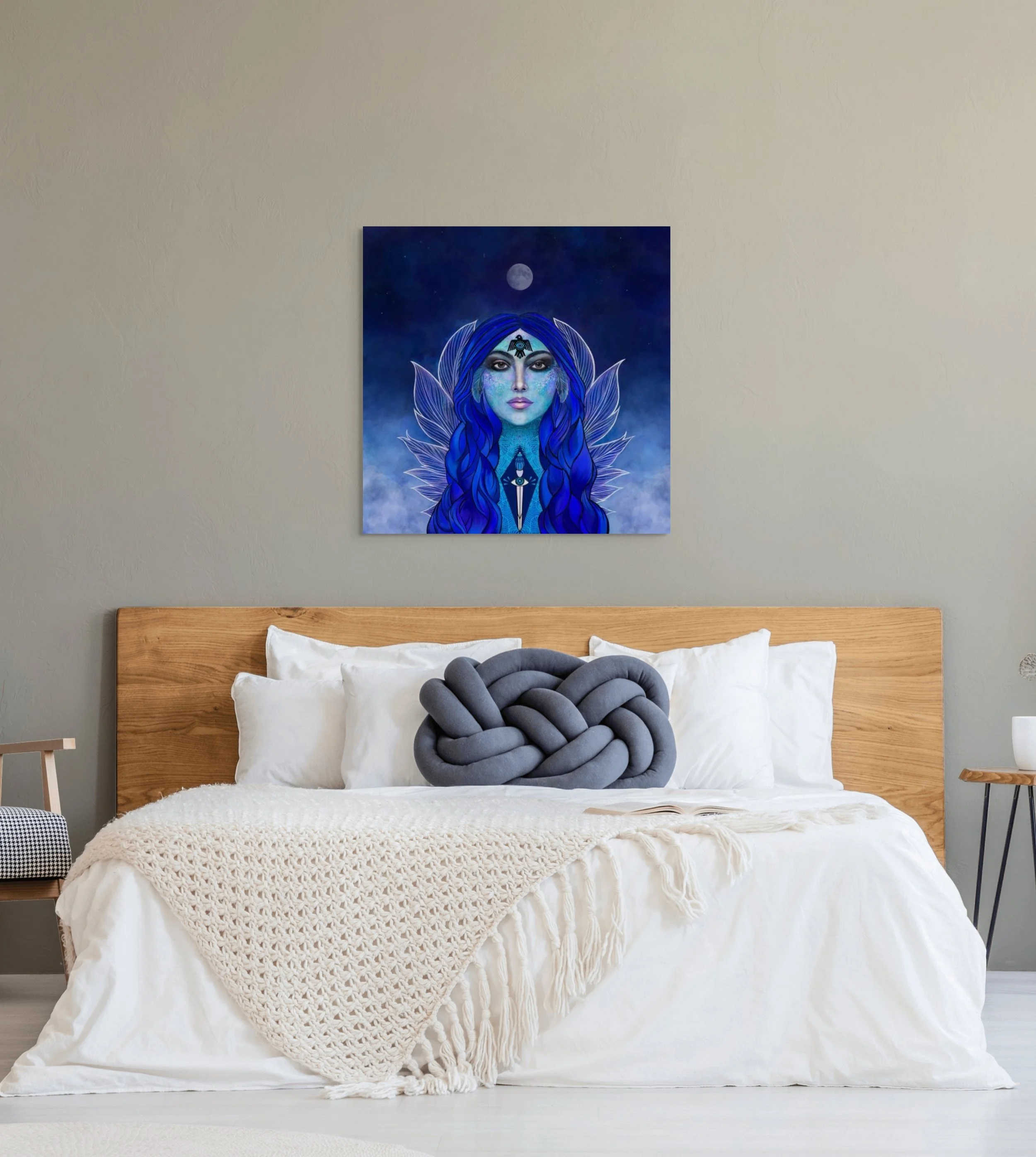 Deep blue spiritual woman portrait wall art hanging above a bed in a modern bedroom with calming celestial home decor styling.