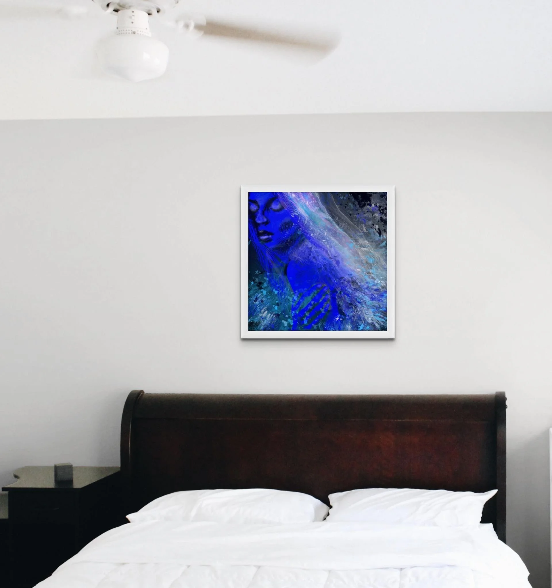 Deep blue coastal woman wall art hanging above a bed in a modern bedroom with dreamy ocean-inspired decor styling.