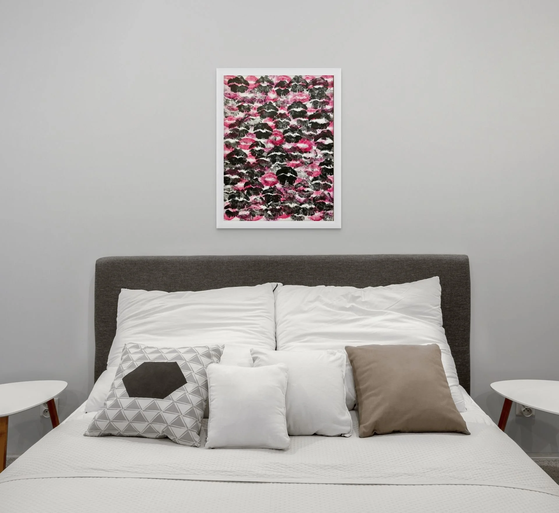 Red and black abstract kiss print hanging above a bed in a dramatic modern bedroom with edgy contemporary decor styling.