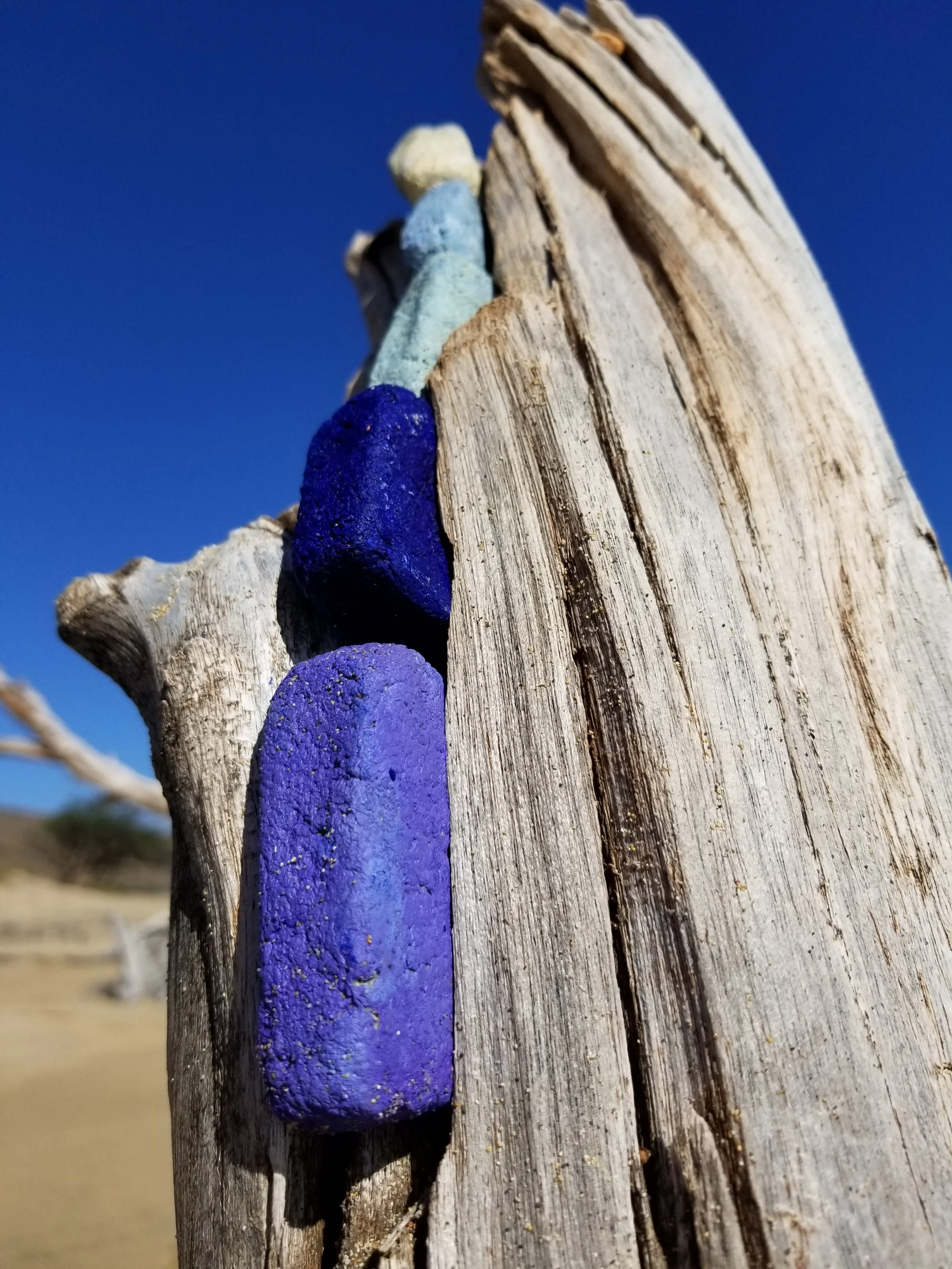 Vertical stack of paper pulp bricks painted with earth pigments and installed in drift wood.