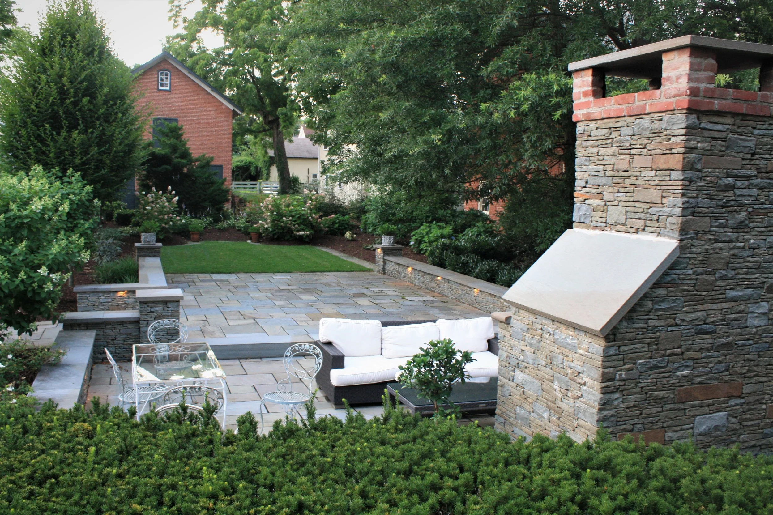 Classic patio. Stone exterior fireplace with bluestone patio and stone seatwalls create this formal and symmetrical courtyard.