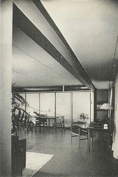 Another view of the living area—this time, towards the dining table at the end of the room, which sits near the storage wall. At the far right is the entry passage to the kitchen. In this photograph, one of room’s pair of large steel ceiling beams is strongly emphasized.