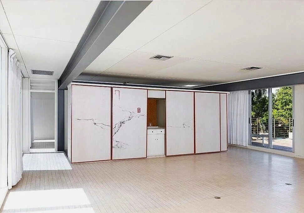 LEFT:     An interior view of the Biggs Residence in 1959—showing the house in its original state, as designed by Paul Rudolph.  This view of the central living-dining area is towards the dining table at the end of the room, which sits near the storage wall. At the far right is the entry passage to the kitchen. In this photograph, one of room’s pair of large and prominent steel ceiling beams is clearly seen     ABOVE:     As of 2016, when this photograph was taken, the house’s main living space still retained its essential character of a spacious openness in its center, as well as other Rudolph-designed features: the emphatically displayed steel structure, and the wall of storage (behind moving panels) at one end of the room