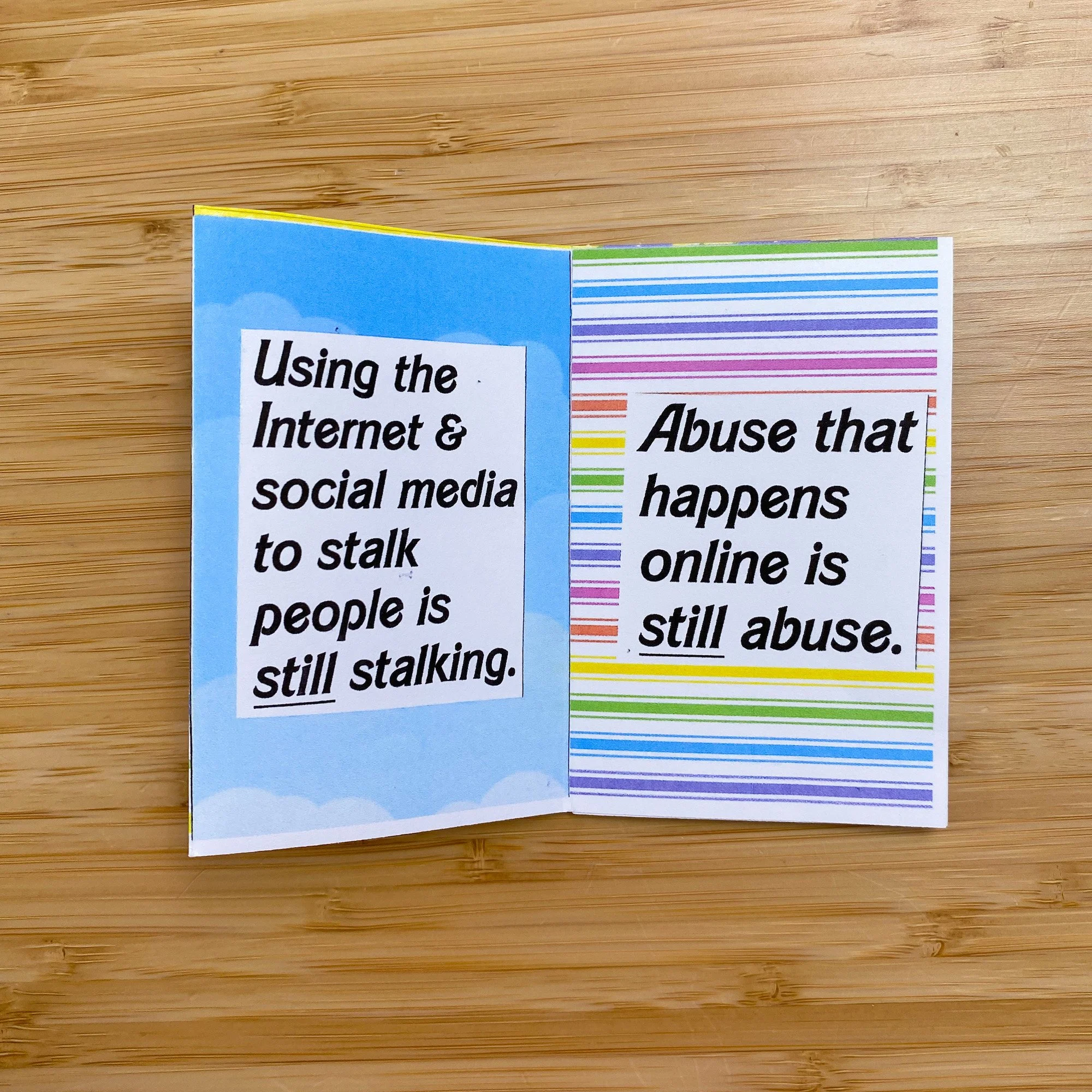  Image description: A flat lay of Karina's mini-zine, "On Digital Violence &amp; Online Abuse," on a desk. The first page has clouds in the background &amp; reads, "Using the Internet &amp; social media to stalk people is still stalking." The next pa