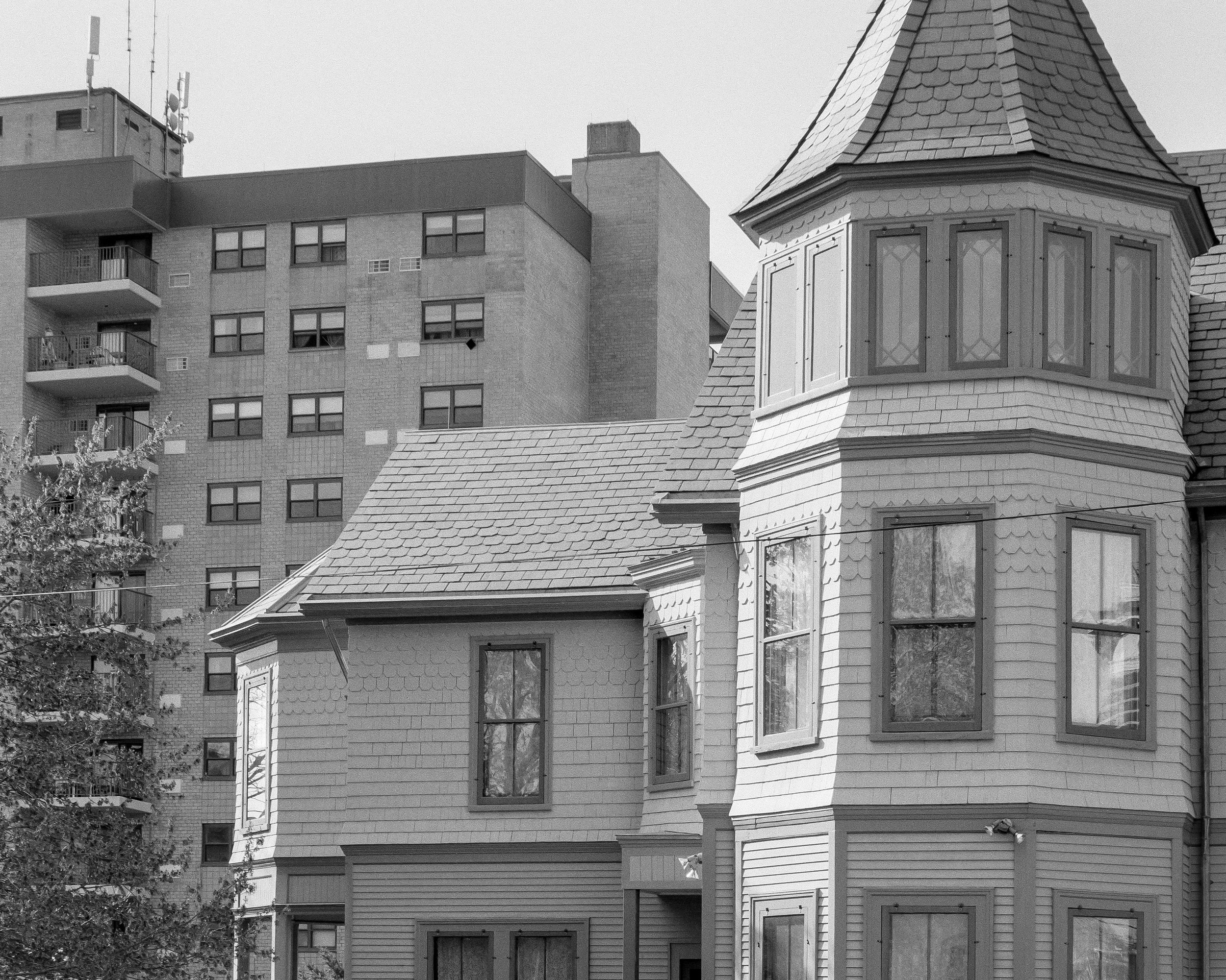 The 1878 building that houses the museum—all gables and turrets and yellow- and green-shingled millwork—sits upon a hill. In its immediate background is a late- midcentury brick high-rise, rectilinear in form with small symmetrical windows and punched- out, boxy balconies. The scene recalls theorist Fredric Jameson’s Postmodernism , in which he writes about the construction of the Wells Fargo Tower in Los Angeles’ historic Bunker Hill neighborhood, observing that Modernism effectuated a “waning of historicity” and “depthlessness” of place.