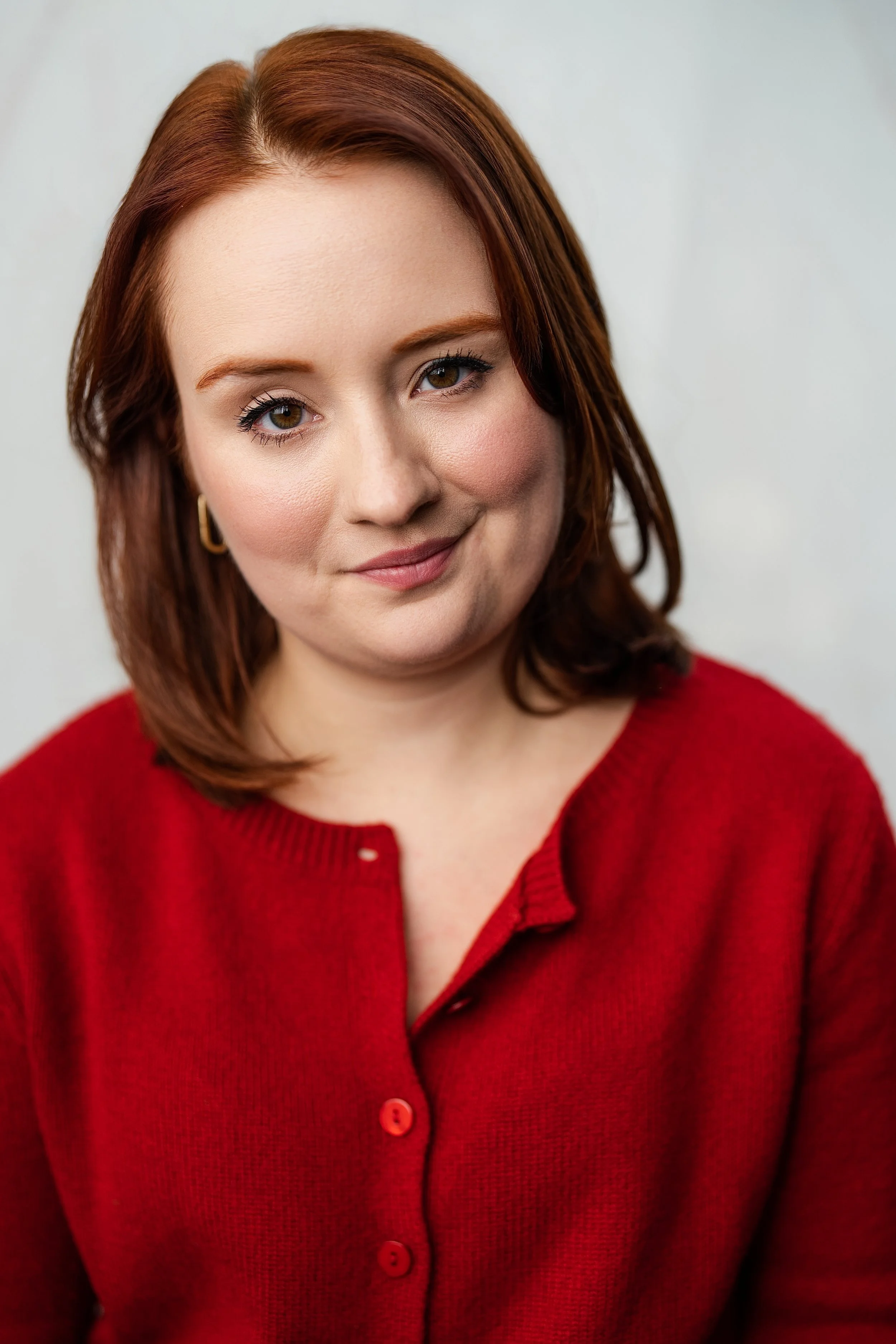 A women with shoulder length red hair in a red cardigan sweater