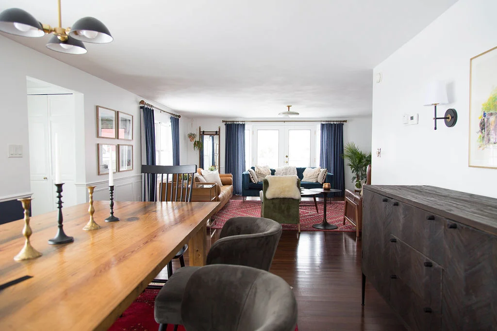View from the dining room into the living room including two couches, accent chairs, and handcrafted dining room table