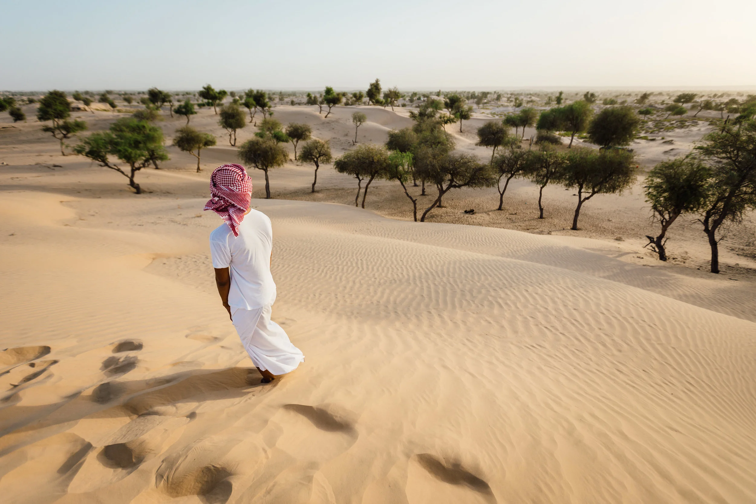 A young Omani man stares off into the distance of the desert of Sharqia.