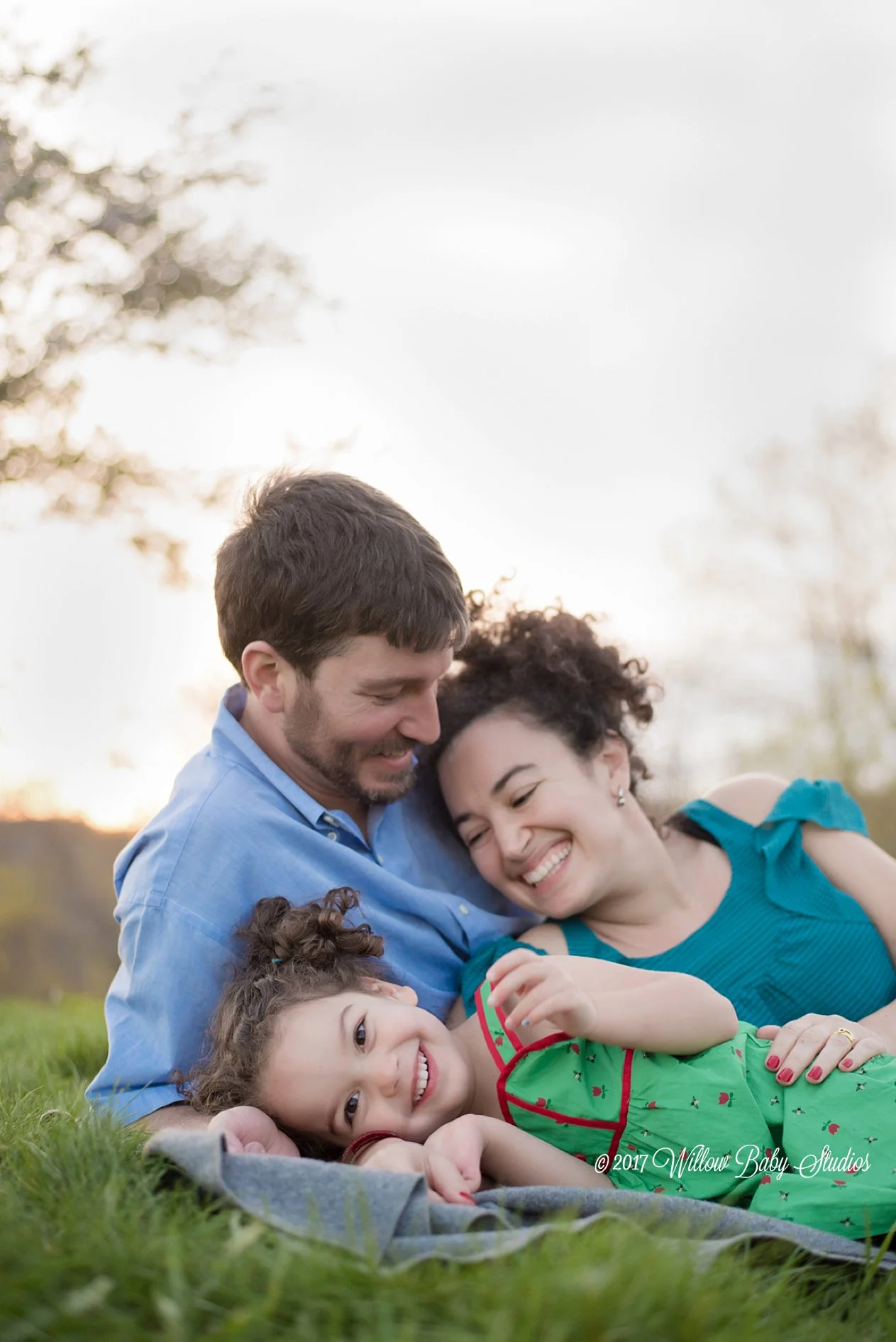 parents-with-young-daughter-snuggling-outside-spring-evening