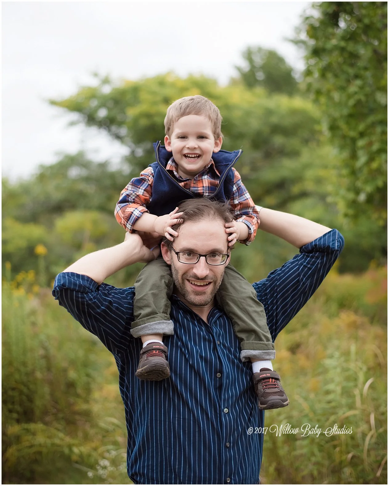 smiling dad with his three year old son on his shoulders