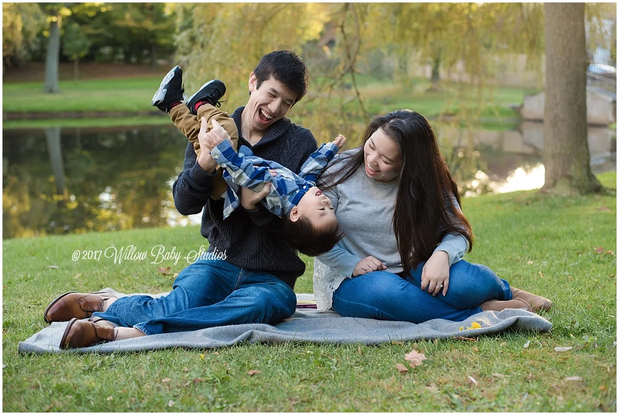 outdoor family photo mom dad and son goofing around on blanket at sunset