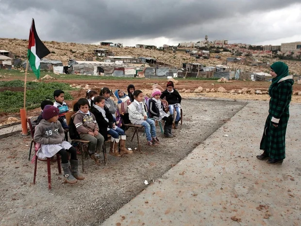 Bedouin children attend school outside in Abu Anwar near the Jewish settlement of Maale Adumim (background), after their classrooms were demolished (AFP)