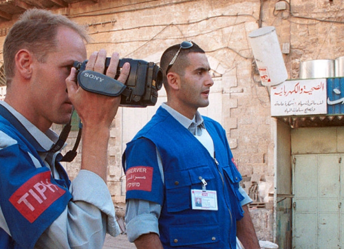 An observer from the Temporary International Presence in Hebron videotapes clashes between Palestinians and Israeli troops November 7, 2000 in the marketplace in the West Bank town of Hebron.