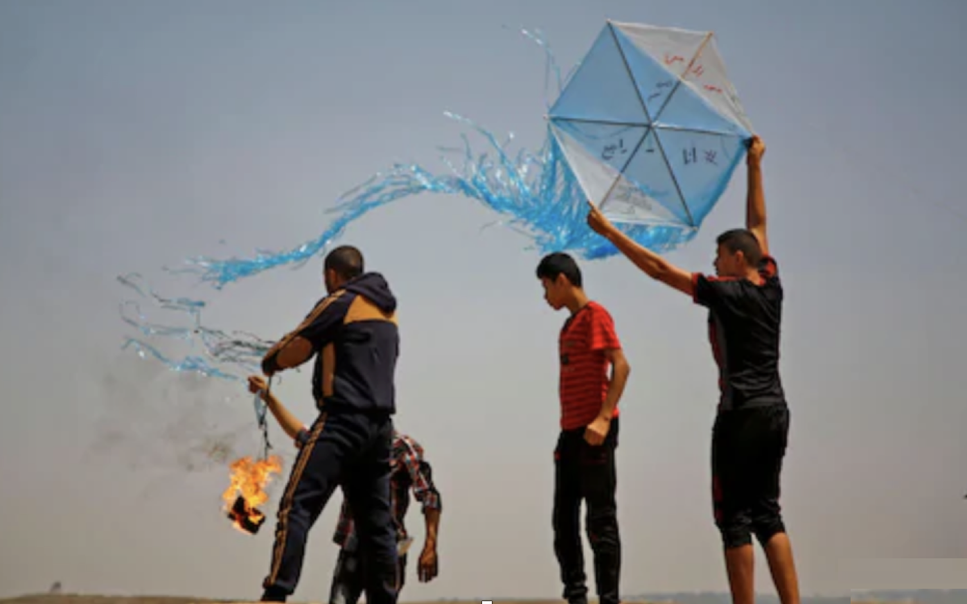 Palestinian protestors prepare to fly a kite loaded with an incendiary during a demonstration along the Gaza-Israel border.