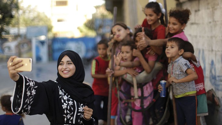 Fatma Abu Musabbeh , 21, uses her cellphone to take a picture for her social media account of children in Deir al-Balah in the central Gaza Strip, Sept. 17, 2017. She and another Gaza woman are among a small number of Instagram stars in Gaza, showing their followers a different side of their homeland than what much of the world may be used to seeing or hearing. (MAHMUD HAMS/AFP/GETY IMAGES)