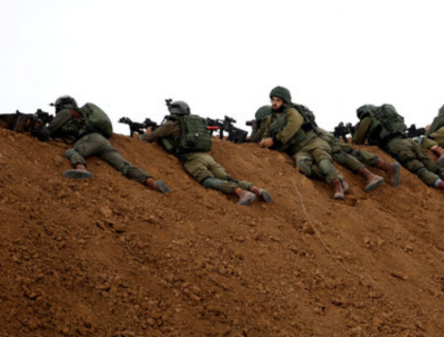 Israeli soldiers are seen next to the border fence on the Israeli side of the border with the northern Gaza Strip, Israel, March 30, 2018.