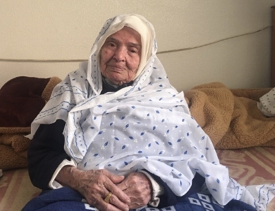 Halima Abudayya, 95, sitting on her bed in her son's house in northern Gaza, dreams of returning to her true home (MEE/Maha Hussaini)