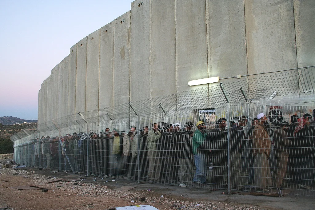 Men and women from all over the Southern West Bank stand in line for hours each morning on their way to work outside of Bethlehem. Photo by delayed gratification.