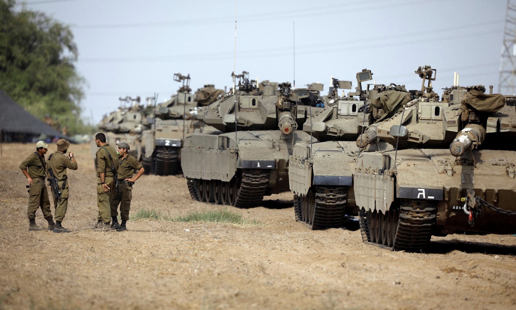Israeli soldiers speak next to tanks as military armoured vehicles gather in an open area near Israel's border with the Gaza Strip October 18, 2018. REUTERS/Amir Cohen