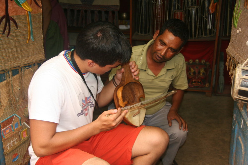 Anthony learning Nepali musical instrument