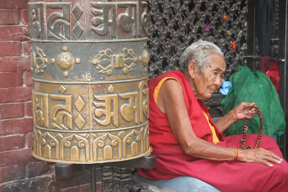 Old Tibetan monk and prayer wheel