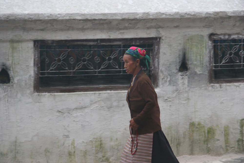 Tibetan woman and prayer wheels around base of Boudhinath stupa