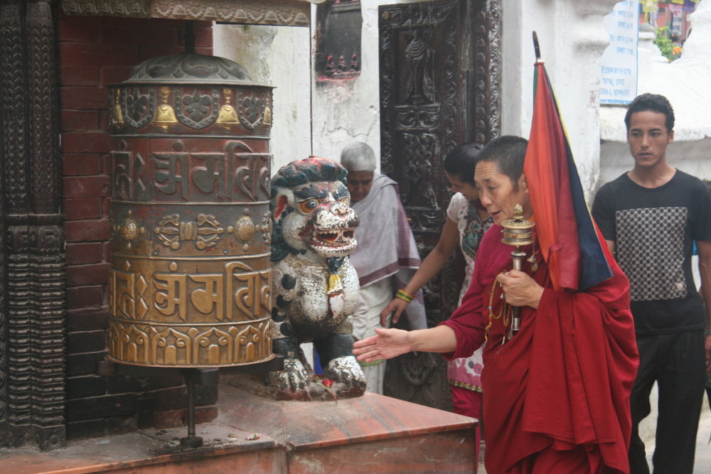 Tibetan woman and prayer wheels around base of Boudhinath stupa