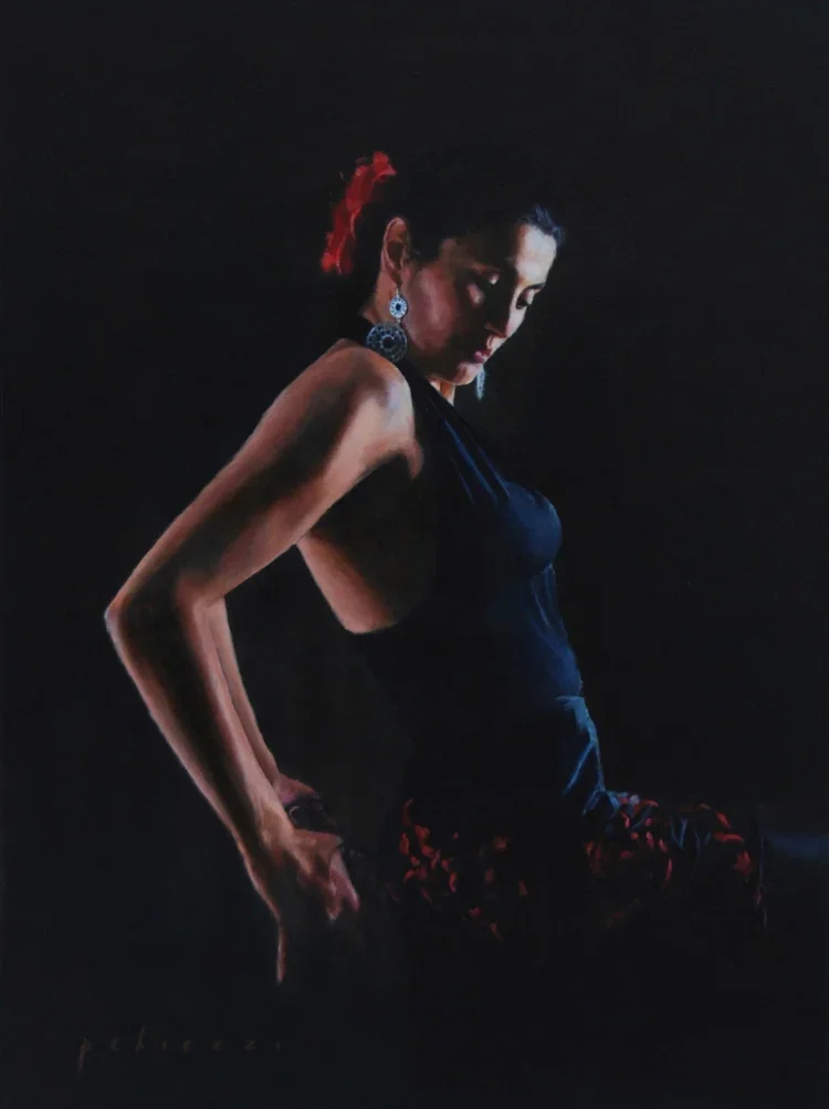 A woman with dark hair and earrings, dressed in a black top and dark pants with red patterns, is in a dark setting with dramatic lighting highlighting her profile and arm.