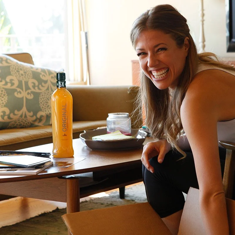 Woman Smiling With LIMU ORIGINAL Antioxidant Drink on Table