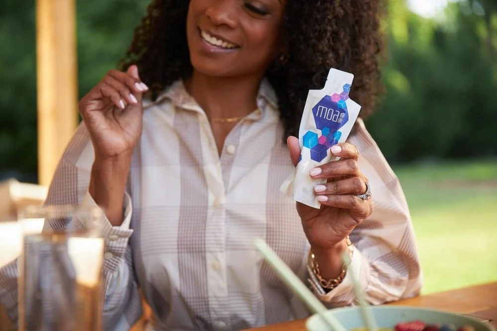 Woman Holding a Pouch of Moa II - Nutritional Supplement Drinks - in Her Left Hand